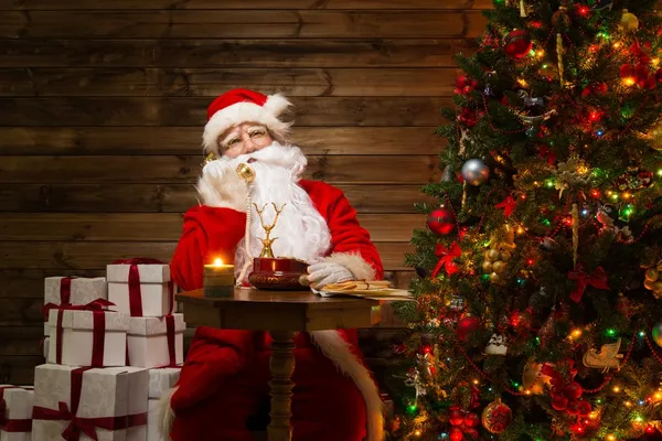 Papai Noel com telefone em casa de madeira interior — Fotografia de Stock