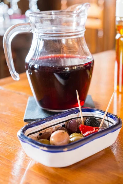 Сангрийский кувшин с тарелкой небольших вкусных закусок на столе — стоковое фото