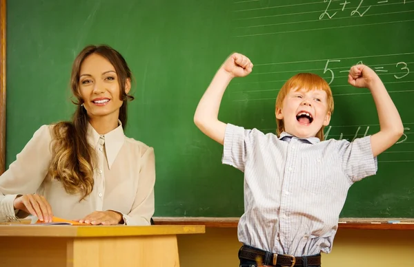 Piccolo ragazzo rosso felice che risponde vicino alla lavagna a scuola — Foto Stock