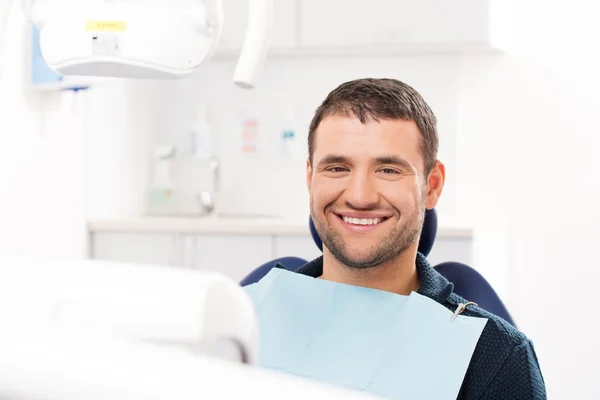 Jeune homme souriant à la chirurgie du dentiste — Photo