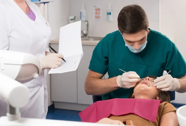 Mladý muž lékař, asistent žena a žena pacient v zubní ordinaci — Stock fotografie