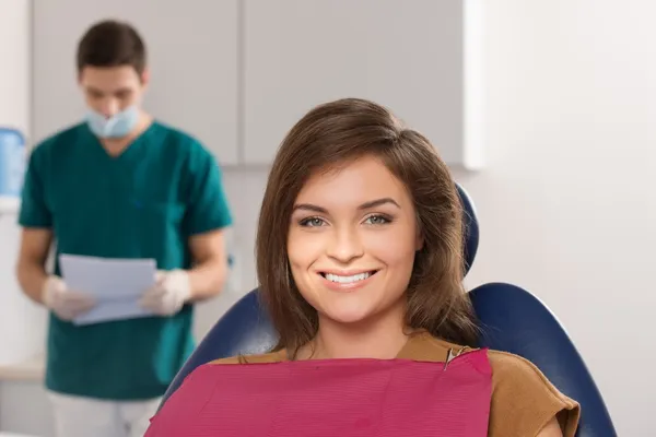 Dentista masculino a ler o cartão do paciente feminino — Fotografia de Stock