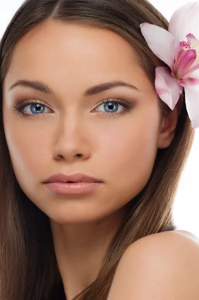 Young brunette girl with beautiful smile and orchid flower in her hair Royalty Free Stock Photos