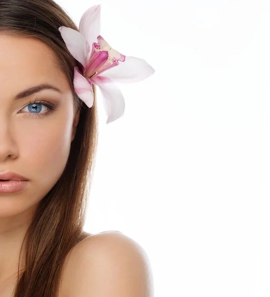 Beautiful young brunette woman with blue eyes and orchid flower in her hair Royalty Free Stock Images
