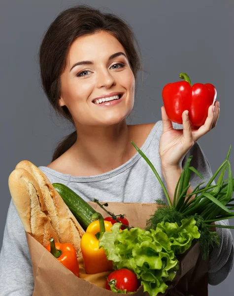 Glimlachend jonge brunette vrouw met kruidenier zak vol met verse groenten — Stockfoto