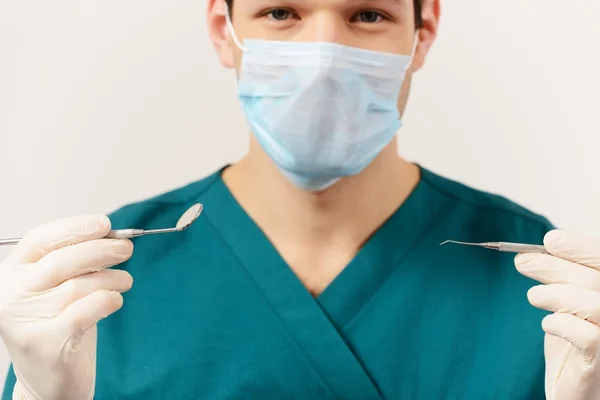 Young man dentist holding dental tools — Stock Photo, Image