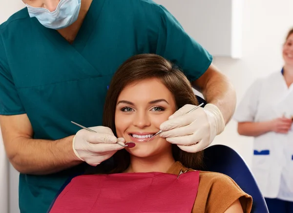 Mujer joven y hombre médico con su asistente en la cirugía del dentista — Foto de Stock