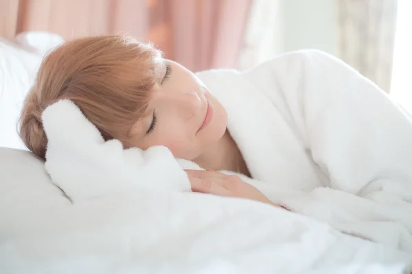 Mulher bonita em roupão de banho com um corte de cabelo curto deitado em uma cama — Fotografia de Stock