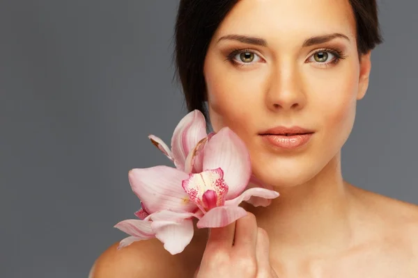 Mulher morena bonita nova com flores de orquídea — Fotografia de Stock