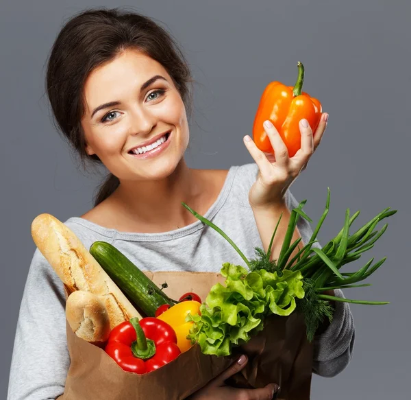 Sorrindo jovem morena com saco de supermercado cheio de legumes frescos — Fotografia de Stock