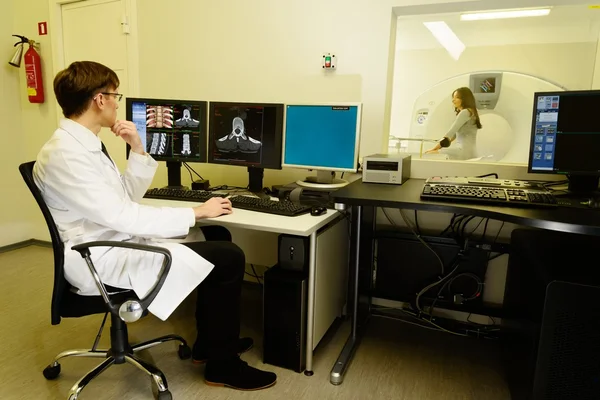 Jovem médico sentado atrás de monitores em um laboratório de tomografia computadorizada — Fotografia de Stock