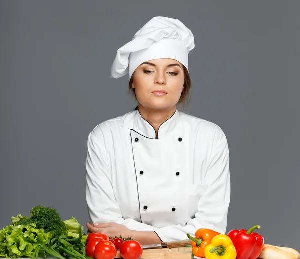 Vacker ung kvinna kock med färska grönsaker på skärbräda — Stockfoto