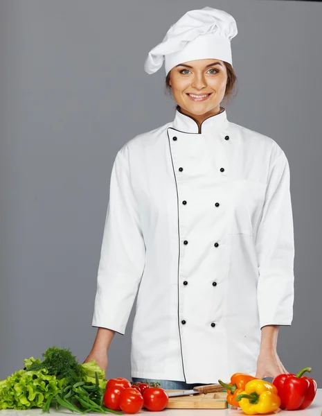 Mulher bonita cozinheiro com legumes frescos na tábua de corte — Fotografia de Stock