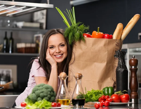 Jeune femme avec sac d'épicerie plein de légumes frais sur une cuisine moderne — Photo