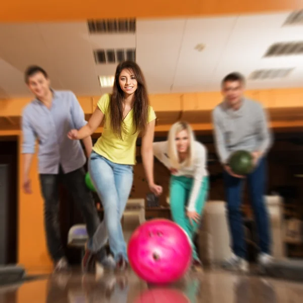 Grupp fyra unga leende människor spelar bowling — Stockfoto
