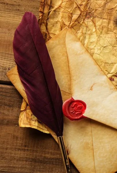 Envelope and quill pen on vintage paper over wooden background — Stock Photo, Image