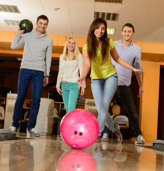 Groupe de quatre jeunes gens souriants jouant au bowling — Photo
