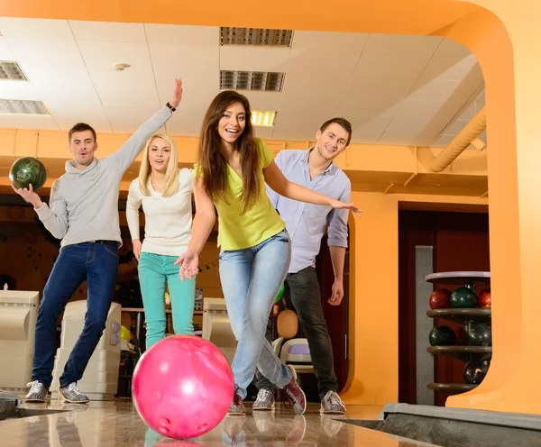 Група з чотирьох молодих усміхнених людей, які грають у боулінг — стокове фото