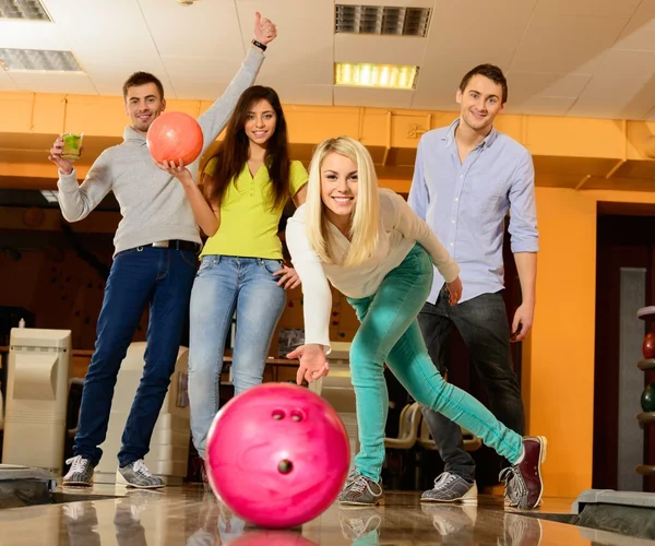 Groep van vier jonge glimlachende mensen spelen bowling — Stockfoto