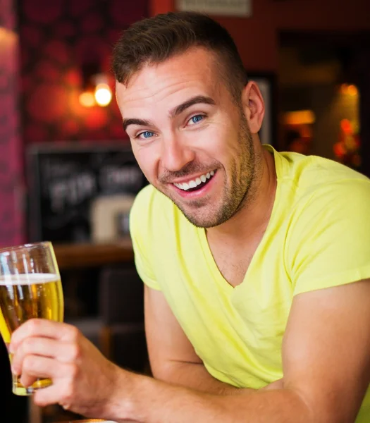 Schöner junger Mann mit leichtem Bier in einer Kneipe — Stockfoto
