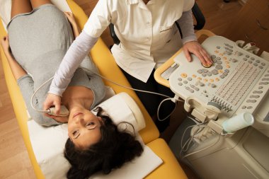 Young woman doing neck ultrasound examination at hospital clipart