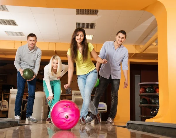 Grupo de cuatro jóvenes sonriendo jugando a los bolos — Foto de Stock