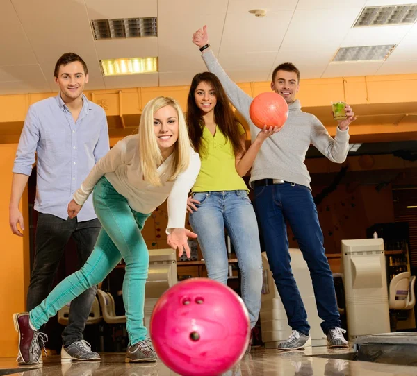 Grupo de cuatro jóvenes sonriendo jugando a los bolos — Foto de Stock