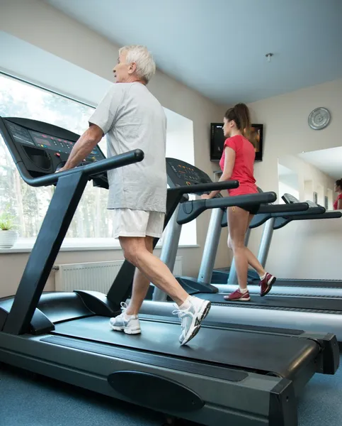 Senior homme et jeune femme marchant sur un tapis roulant — Photo