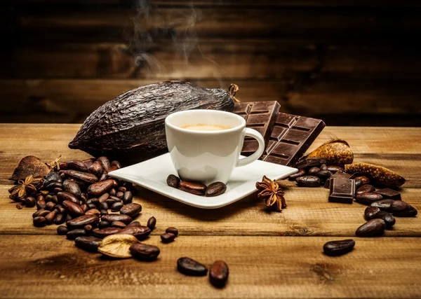 Koffiekopje op een houten tafel onder koffiebonen en donkere chocolade — Stockfoto