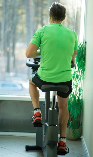 Man doing exercise on a bike in a fitness club — Stock Photo, Image