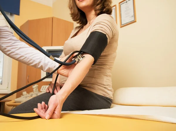 Young pregnant woman in ultrasound examination measuring blood pressure — Stock Photo, Image