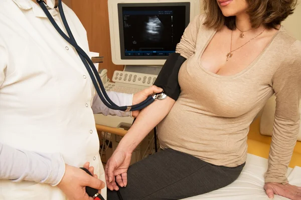 Jovem grávida no exame ultra-sonográfico medindo a pressão arterial — Fotografia de Stock