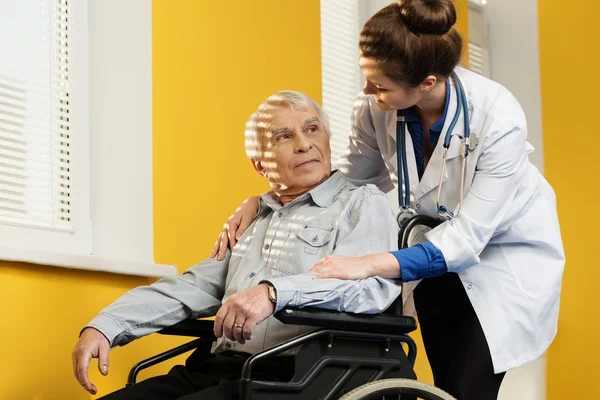 Cheerful young nurse woman with senior man in wheelchair — Stock Photo, Image