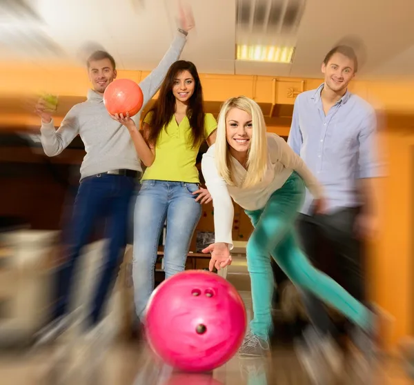 Grupp fyra unga leende människor spelar bowling — Stockfoto