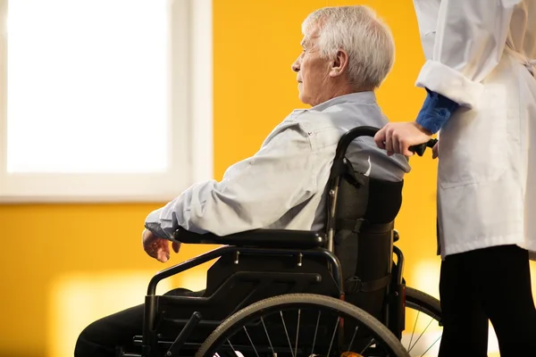 Infirmière femme avec homme âgé en fauteuil roulant r — Photo