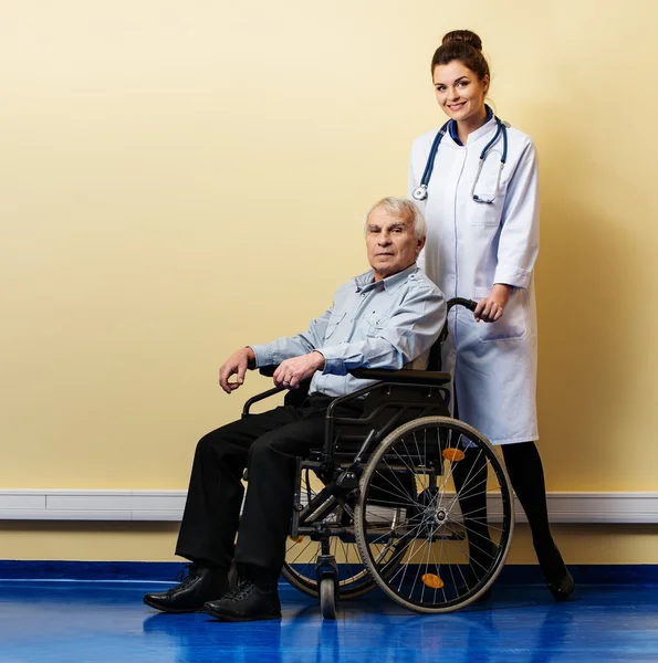 Vrolijke jonge verpleegster vrouw met senior man in rolstoel — Stockfoto