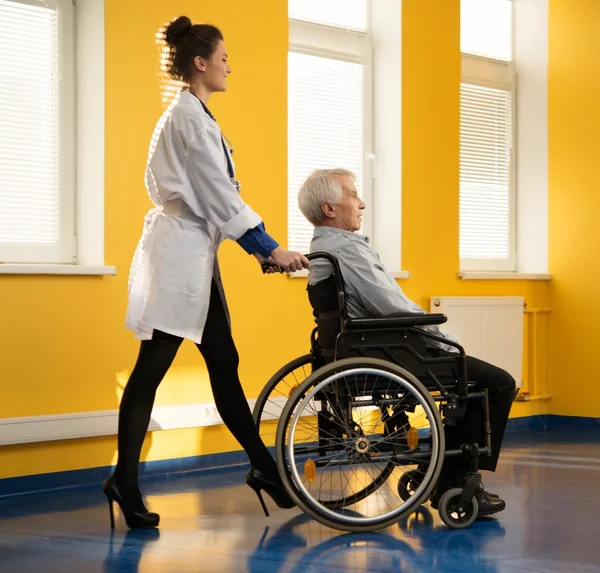 Vrolijke jonge verpleegster vrouw met senior man in rolstoel — Stockfoto