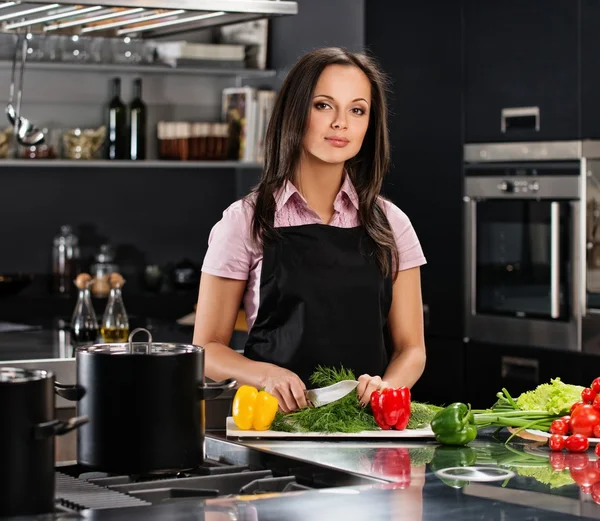 Giovane donna allegra in grembiule sulla cucina moderna tagliare verdure — Foto Stock