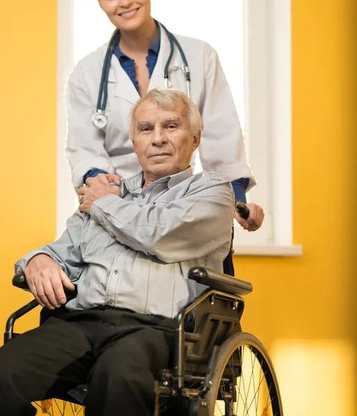 Jovem enfermeira alegre com homem sênior em cadeira de rodas — Fotografia de Stock