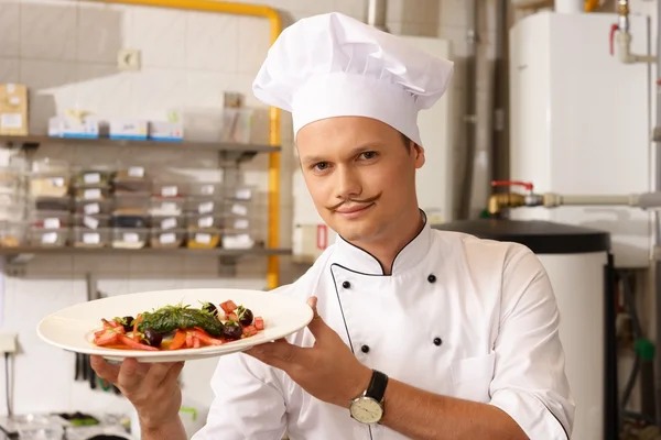 Молодой шеф-повар с изысканной едой на кухне в ресторане — стоковое фото