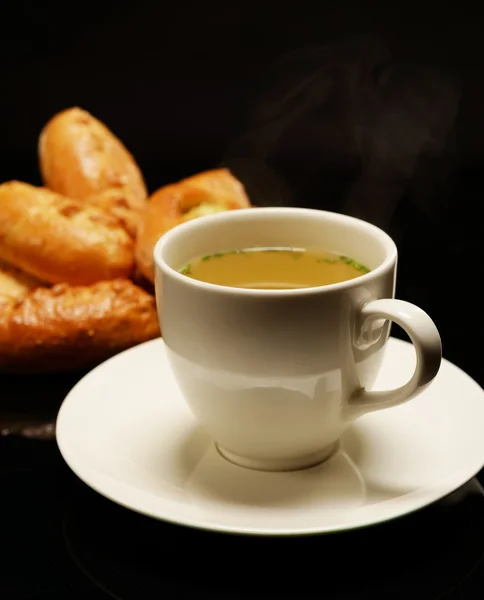 Bullion chaud dans une tasse avec des tartes savoureuses — Photo