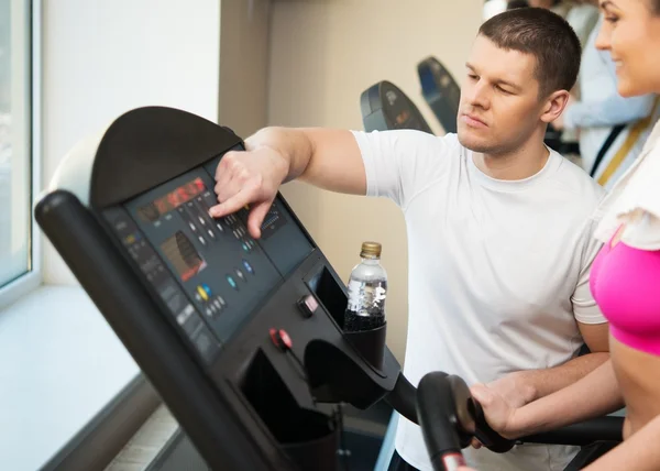 Trainer spiega ad una giovane donna come usare il tapis roulant nel fitness club — Foto Stock