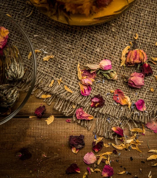 Blume Tee Blütenblätter auf Sacktuch über Holz Hintergrund — Stockfoto