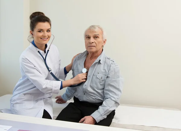 Uomo anziano e medico donna con stetoscopio — Foto Stock