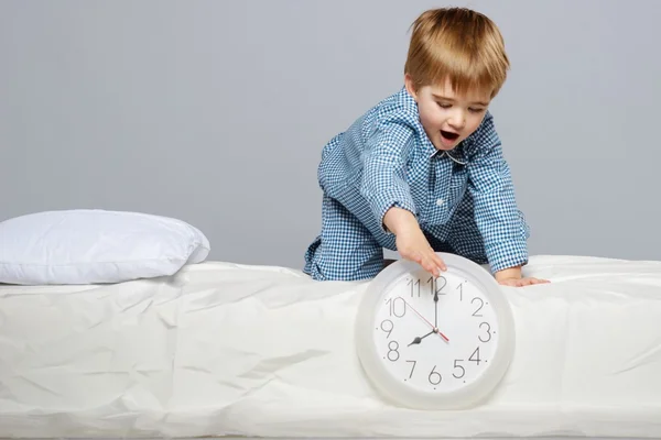 Little boy in blue pyjamas with clock — Stock Photo, Image