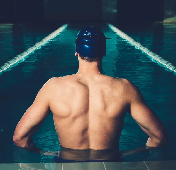 健壮的年轻人在游泳池里顶蓝色的帽子 — 图库照片