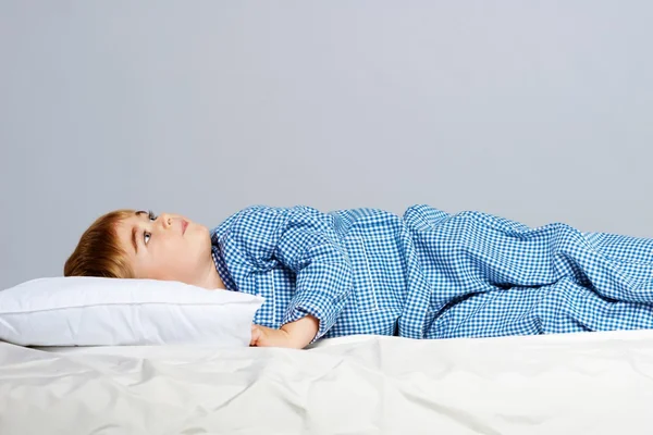 Liten pojke bär blå pyjamas i sängen — Stockfoto