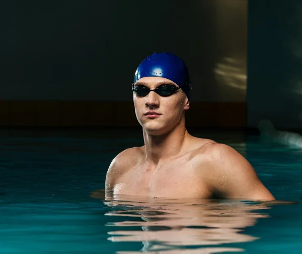 Muscoloso giovane in berretto blu in piscina — Foto Stock