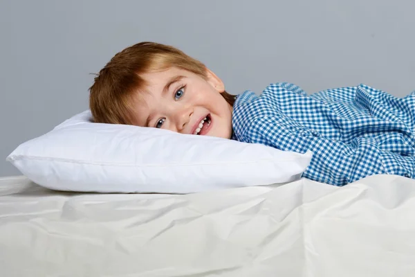 Menino vestindo pijama azul na cama — Fotografia de Stock