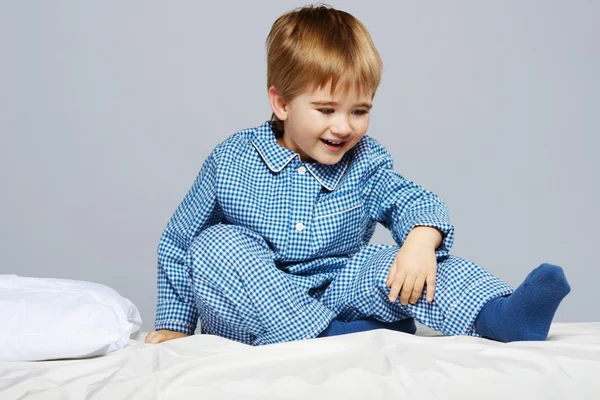 Μικρό αγόρι φορώντας πιτζάμες μπλε στο κρεβάτι — Φωτογραφία Αρχείου